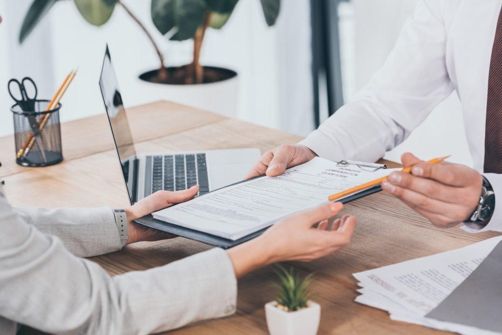 businessman giving compensation claim form to woman at workplace