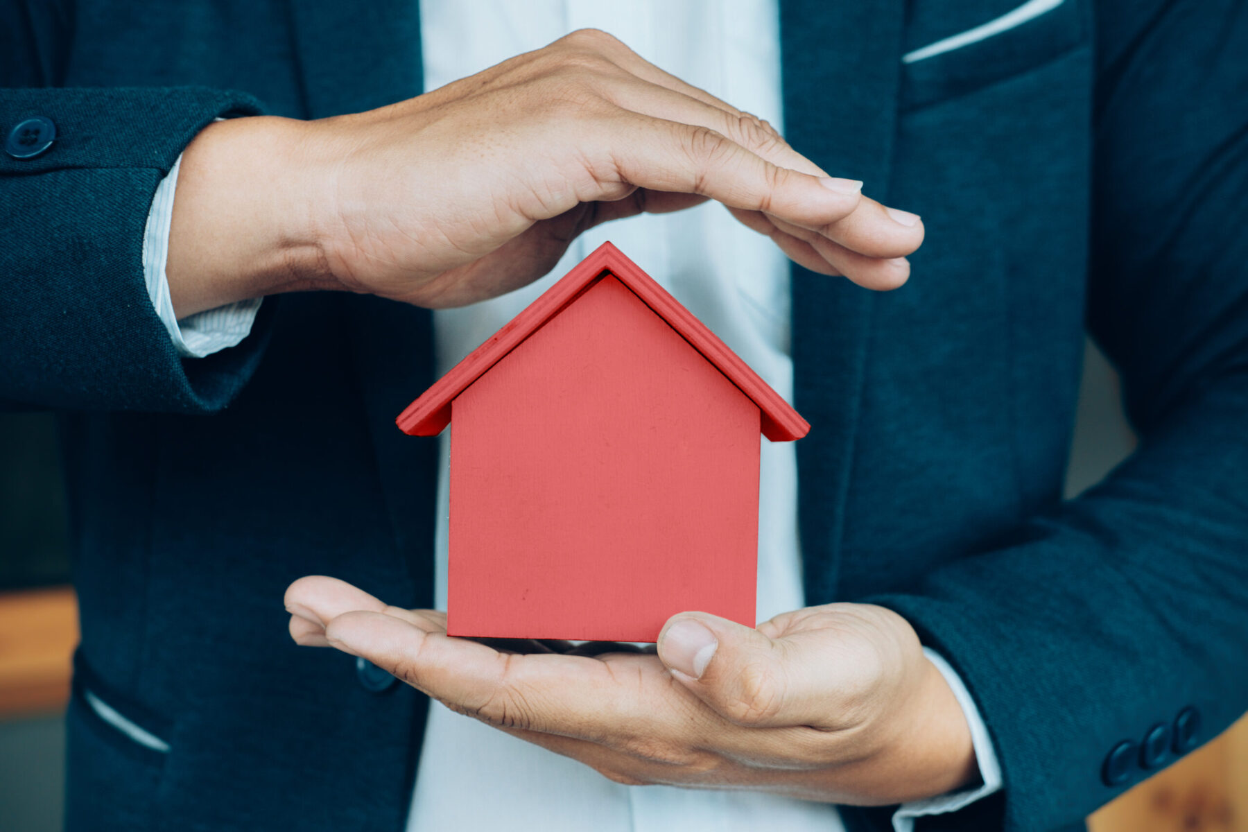 Business man hand hold the house model saving small house. House insurance